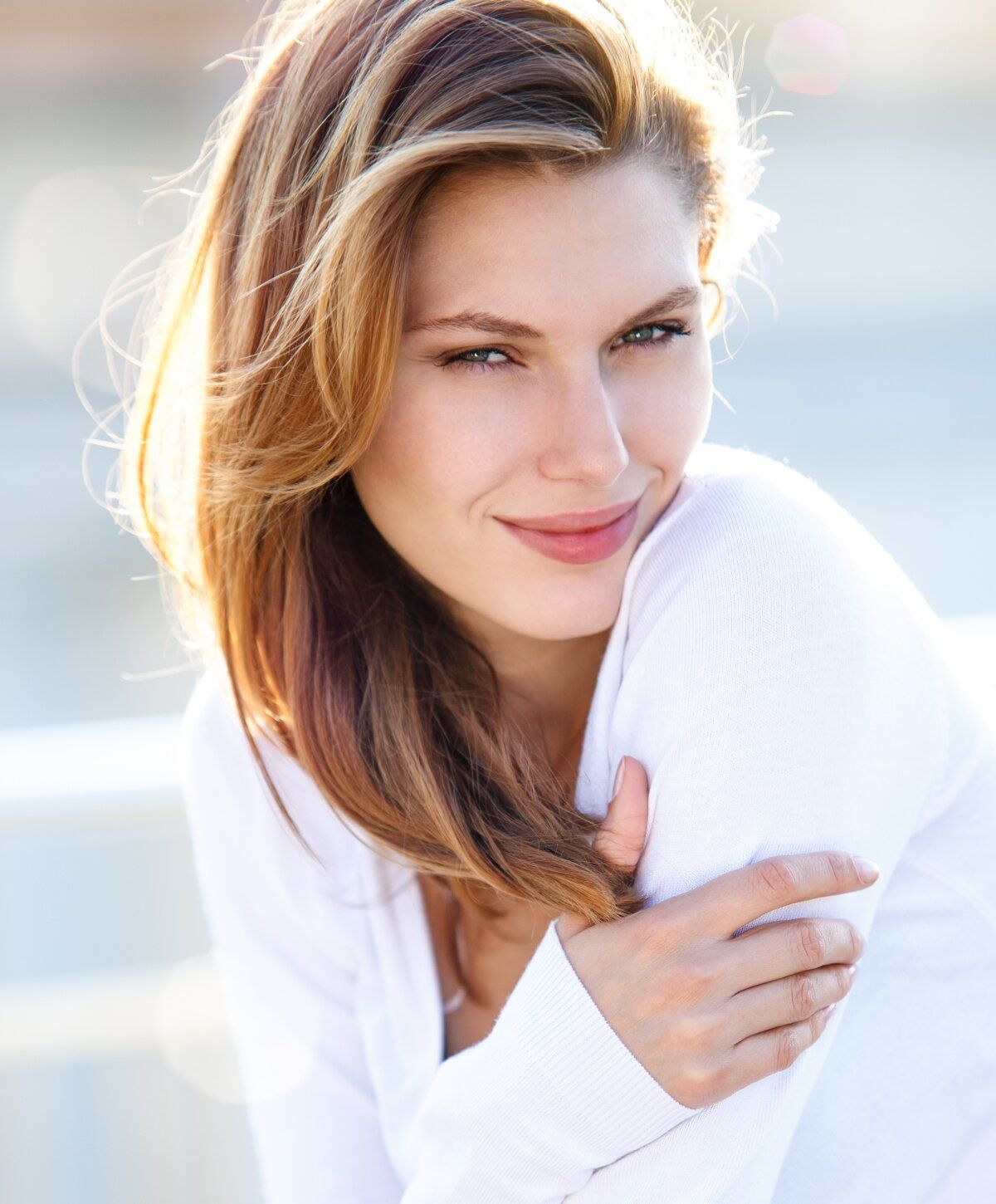 Smiling woman with long hair in sunlight.