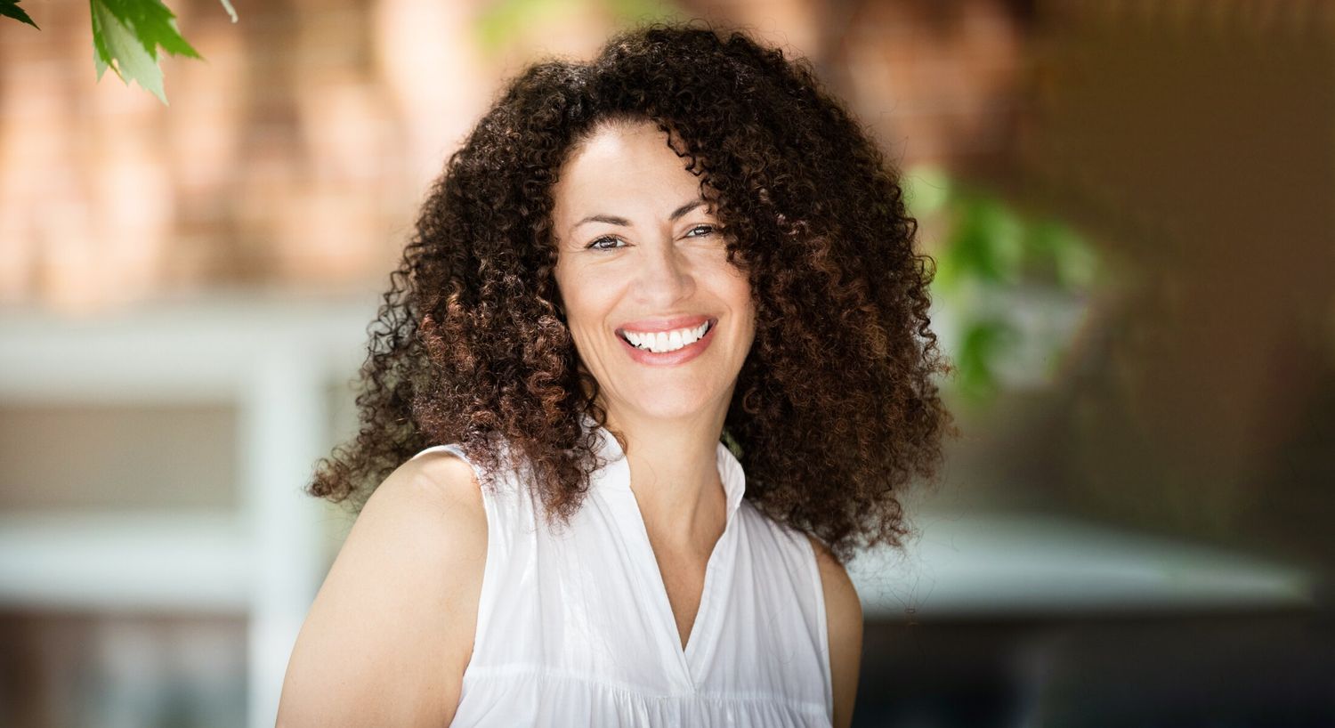 Smiling woman with curly hair outdoors.
