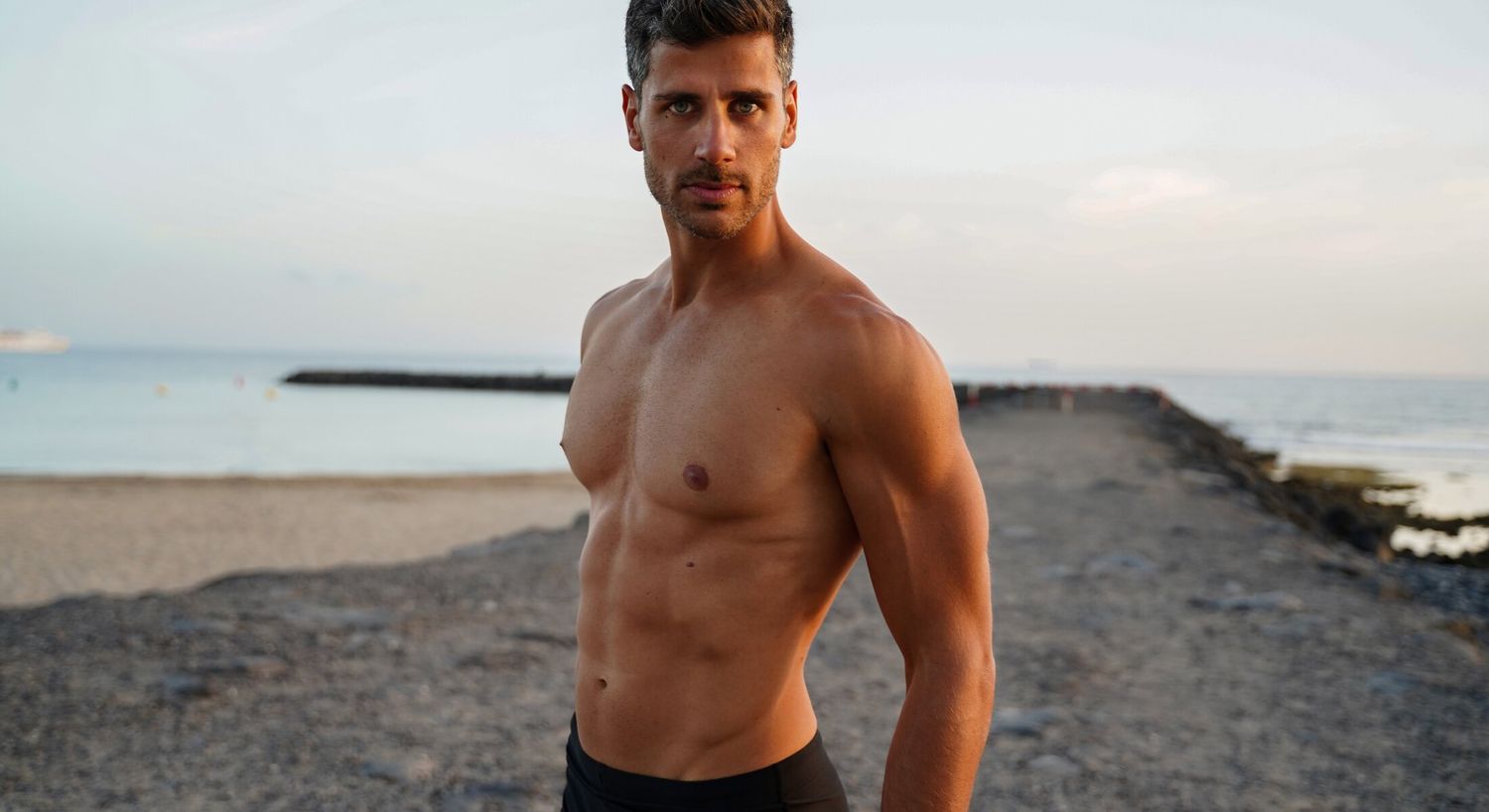 Man posing by the beach at sunset.